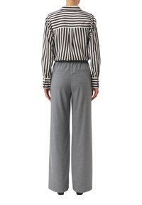 Koszula w paski z kołnierzykiem na guziki i długimi rękawami, połączona z szarymi, szerokimi spodniami z elastycznym pasem i tylnymi kieszeniami.