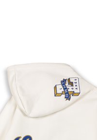Kremowa bluza z kapturem z haftowanym niebiesko-żółtym logo na ramieniu, z blokowymi literami i wstążkowymi akcentami. Miękka struktura.