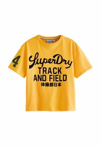 Geel katoenen T-shirt met de opdruk "SuperDry" en "TRACK AND FIELD" in marineblauwe letters. Bevat een groen nummer "4" op de mouw. Korte mouwen.