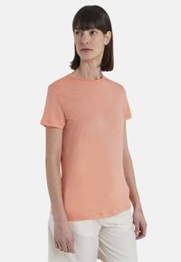 T-shirt a maniche corte, con colletto tondo, di colore corallo chiaro, realizzata in tessuto leggero con una texture morbida e design minimale.