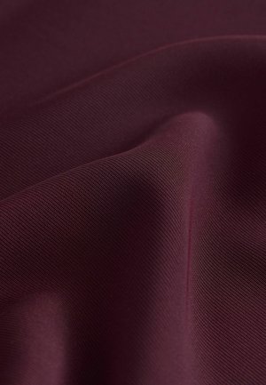 Burgundi värvi kangas, millel on sile ja tekstureeritud pind, kus on peen ribastus. Voltitud ja langev, tuues esile selle sügavuse ja sära.