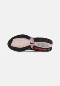 Black and pink sneaker sole with textured rubber tread, transparent air cushioning, and red circular accents near the heel.