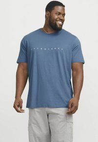 Blå crew-neck T-shirt lavet af glat bomuld med korte ærmer, prydet med et hvidt trykt logo, der læser "JACK & JONES" hen over brystet.