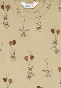 Beiger Stoff mit verspielten Illustrationen von Hasen, die an Schnüren und braunen Luftballons hängen, die gestreifte Oberteile oder gepunktete Röcke tragen.