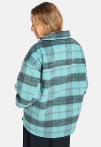Turquoise fleece jas met een ruitpatroon in donkergrijze lijnen, een brede kraag en een ontspannen pasvorm met verlaagde schouders.