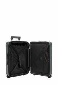 Valise rigide grise avec un extérieur texturé, une poignée rétractable et quatre roues. L'intérieur est doublé de tissu noir et comporte des sangles croisées.