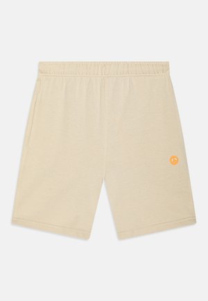 Pantalones cortos de algodón beige con cinturilla elástica, bolsillos laterales y un pequeño símbolo de paz naranja bordado en la parte inferior de la pierna izquierda.