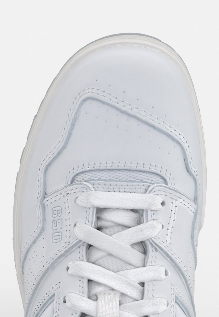 Zapatilla deportiva blanca con un upper de cuero suave, acentos perforados, punta redonda, cordones planos y una suela acolchada. Marcada con "650".