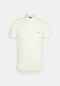 Polo tričko v světle žluté bavlně, s trojicí knoflíků a malým logem na levé hrudi. Krátké rukávy a rovný spodní lem.