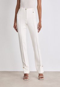 Weiße Tailored-Hosen mit hoher Taille, flachem Vorderteil und seitlichen Paspeln. Verfügt über Akzente in goldfarbener Hardware und ein gerades Bein-Design.