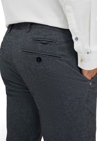 Grijze textuur broek met een slim fit, met twee achterzakken, waarvan er één met een knoop is beveiligd, en een tailleband met riemlussen.