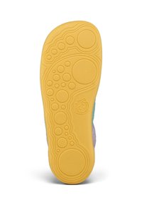 Semelle en caoutchouc jaune d'une chaussure avec des motifs circulaires et un petit visage souriant en relief près du talon.