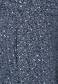 Tissu imprimé de feuilles en noir et blanc avec une texture douce, présentant un motif répété de feuilles stylisées sur un fond clair.