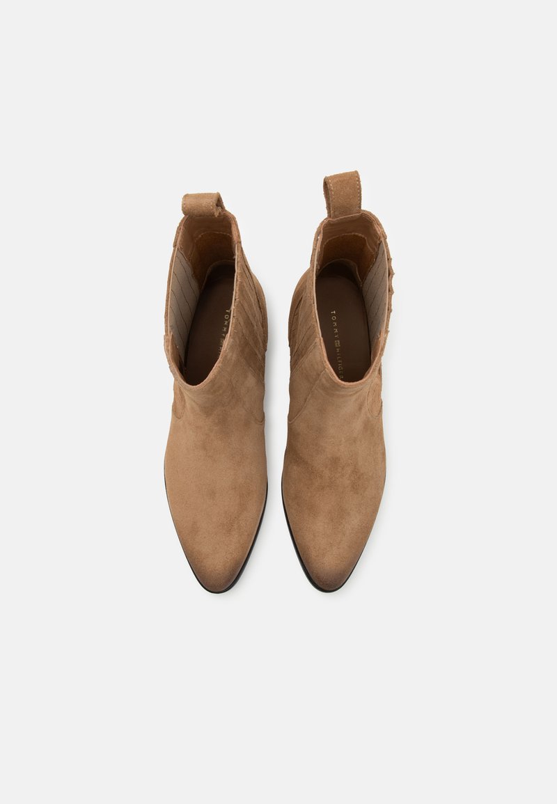 Bottes de cheville en suède marron clair avec bouts pointus, couture décorative sur les côtés et languettes de tirage à l'arrière pour un enfilage facile.