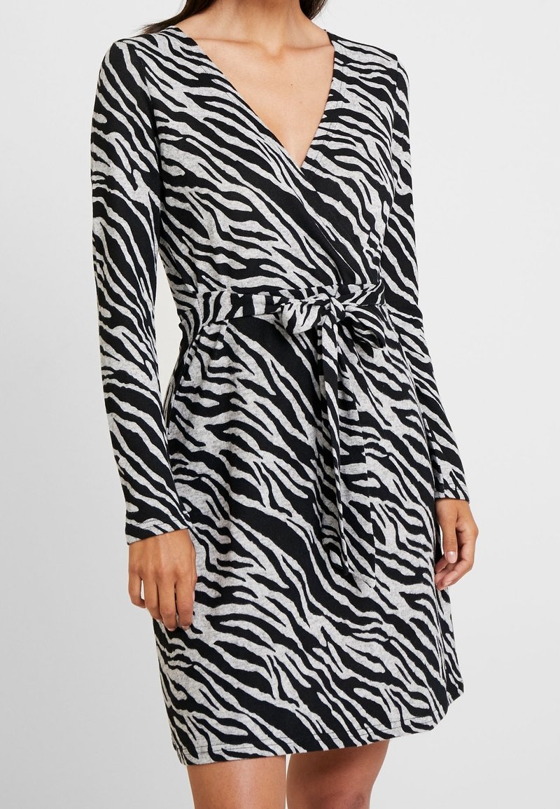 Czarna i szara sukienka w paski zebry, z dekoltem w serek, długimi rękawami i materiałowym paskiem w talii. Miękka tekstura i dopasowany krój.
