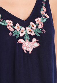 Navy garment showcasing intricate pink and green floral embroidery, featuring a V-neckline and decorative floral patterns at the chest.