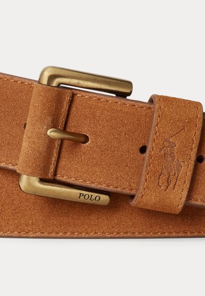 Világosbarna velúr bőr öv rézcsattal, amelyen a "POLO" felirat és az övhurkon dombornyomott Polo játékos logó található.
