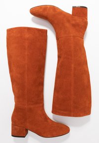 Botas altas de ante en un rico color naranja, con un tacón bloqueado y una textura suave, puntera redondeada y detalles de costura.