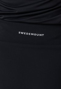 Svart atletisk topp i texturerat tyg, med en rynkad design och den vita loggan "SWEDEMOUNT" i framträdande position.