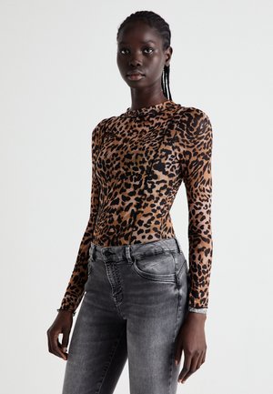 Bodysuit à manches longues léopard en nuances de marron et noir, associé à un jean gris ajusté. Texture lisse et silhouette élancée.
