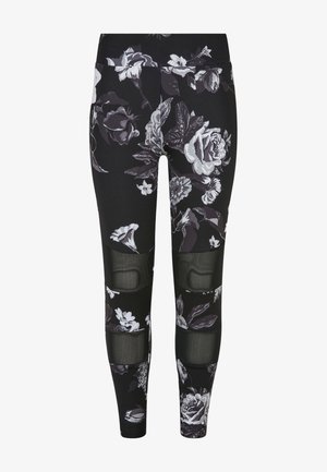 Zwarte legging met een bloemenpatroon in het wit en grijs, met netpanelen op de knieën voor extra textuur en ontwerpelement.