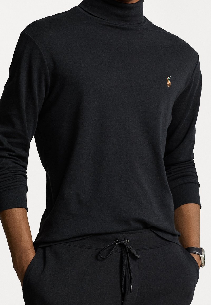 Svart turtleneck sweatshirt med långa ärmar, som har en liten broderad logotyp. Tillverkad av mjukt material med en avslappnad passform och ribbade manschetter.