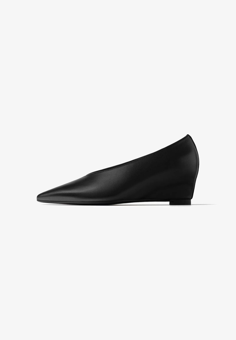 Chaussure compensée noire pour femme à bout pointu et dessus en cuir lisse, vue de profil sur fond blanc.
