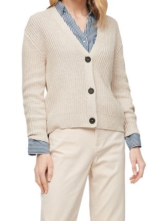 Knit beige cardigan with a v-neck, long sleeves, five dark buttons, and ribbed cuffs over a blue striped shirt. Textured fabric.