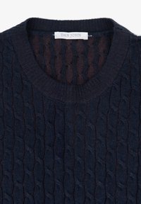 Granatowy sweter dziany z wzorem w warkocze, okrągłym, prążkowanym dekoltem oraz etykietą z napisem "DAN JOHN" blisko kołnierza.