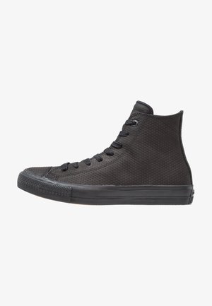 Zapatilla negra de caña alta con parte superior texturizada, cordones negros y suela de goma vista desde el lado exterior sobre fondo blanco.