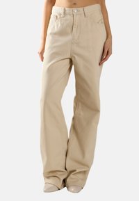 Beige wijde jeans gemaakt van stevig materiaal, met voorzakken, een hoge taille en een ontspannen pasvorm, met subtiele stikdetails.