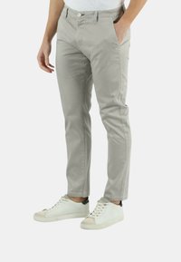 Pantaloni in chambray di cotone grigio chiaro con una vestibilità slim, tasche frontali e chiusura con bottone, abbinati a sneakers bianche.