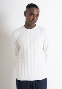 Maglioncino lavorato a maglia bianco con un motivo geometrico sul davanti, colletto e polsini a costine. Maniche lunghe, vestibilità casual.