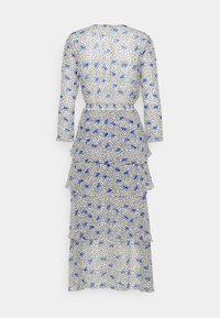 Robe midi blanche à manches longues avec imprimé fleuri bleu et pois noirs, jupe à volants superposés, vue de dos.
