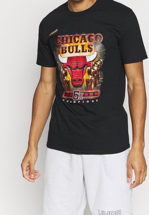 Mann trägt ein schwarzes Chicago Bulls T-Shirt mit Teamlogo, sechs Meisterschaftstrophäen und den Jahren der Siege auf der Vorderseite.