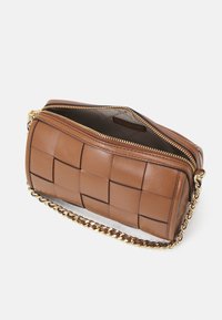 Borsa a tracolla in pelle marrone con design trapuntato, tracolla in catena dorata e chiusura con zip. Texture liscia con una forma rettangolare strutturata.