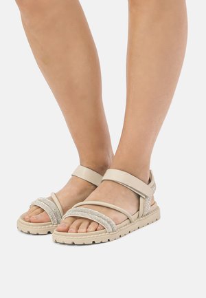 Sandalias beige con múltiples correas, incluyendo un acento de cuentas. Suela texturizada y correa de tobillo ajustable para un ajuste seguro. Diseño de punta abierta.