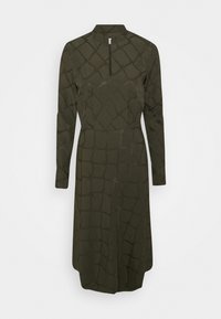 Vestido largo de manga larga en verde oliva con un cuello tipo polo, que presenta un patrón de diamantes texturizado y un corte recto desde la cintura hasta el dobladillo.