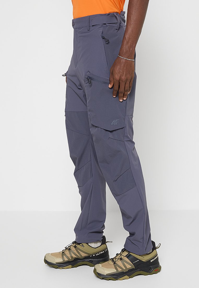 Herren Outdoor-Hosen in Grau aus leichtem, wasserabweisendem Material, mit mehreren Taschen, Reißverschlüssen und verstärkten Nähten für Langlebigkeit.