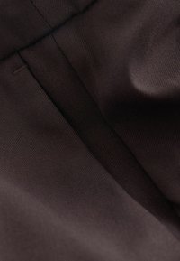 Țesătură de culoare maro închis cu o textură netedă, prezentând un model subtil în dungi și secțiuni pliate, subliniind un design elegant și minimalist.