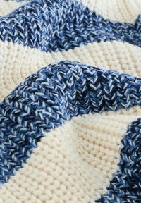 Couverture en tricot présentant des rayures alternées de bleu foncé, bleu clair et crème. Matériau texturé avec une apparence chaleureuse et douce.