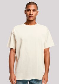 Beige cotton T-shirt with a relaxed fit, short sleeves, and a crew neckline, featuring a smooth texture and minimal design.
