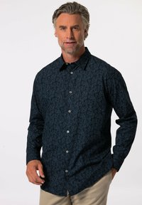 Košile s dlouhým rukávem v námořnické modré barvě se subtilním vzorem listů. Má límeček na knoflíky a klasický střih s předními knoflíky a knoflíkovými manžetami.