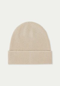 Beige stickad mössa med ribbad textur, som har en vikt kant och sitter tätt. Materialet ser mjukt och varmt ut.