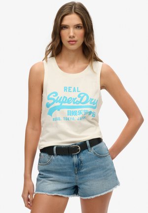 Canotta crema con stampa grafica blu "SuperDry", abbinata a pantaloni corti in denim sbiadito e una cintura nera, con scollatura rotonda e design senza maniche.
