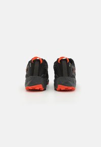 Schwarze Trail-Laufschuhe mit orangefarbenen Akzenten, strukturierten Sohlen und Zuglaschen. Verfügt über ein atmungsaktives Obermaterial und verstärkten Fersenhalt.