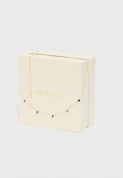 Colar dourado com pequenas contas pretas, apresentado numa caixa de marfim com o logótipo "PERSÉE PARIS" estampado a ouro. Detalhe da corrente visível.