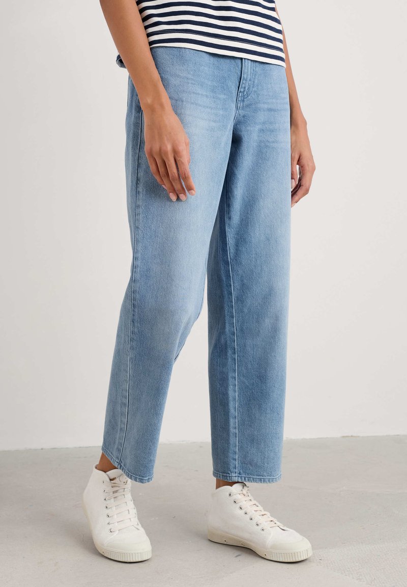 Jeans en denim bleu clair à jambe large avec une taille haute, présentant un design classique à cinq poches et une texture douce, légèrement usée.