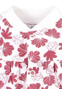 Witte stof met roze en rode bladdessins, voorzien van een witte ronde kraag en twee witte drukknoopjes op het verzamelde materiaal.