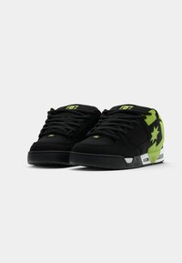 Schwarze Sneaker mit grünen Akzenten, ausgestattet mit einem strukturierten Wildleder-Obermaterial, runden Schnürsenkeln, einer gepolsterten Sohle und einem Stern-Design an der Außenseite.